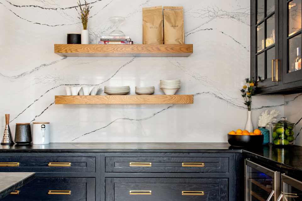 modern kitchen with black cabinets, marble backsplash and gold hardware